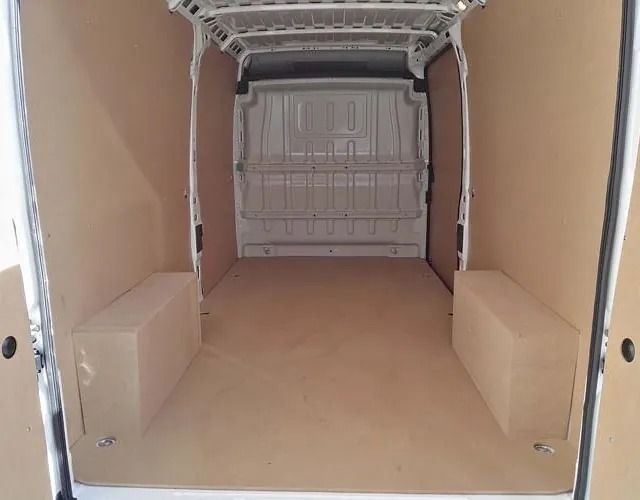 El interior de una furgoneta blanca con suelo de madera.