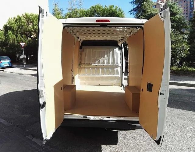 La parte trasera de una furgoneta blanca con las puertas abiertas.