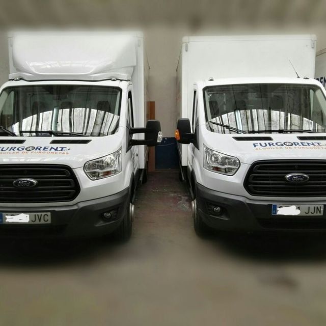 Dos furgonetas Ford blancas están estacionadas una al lado de la otra.