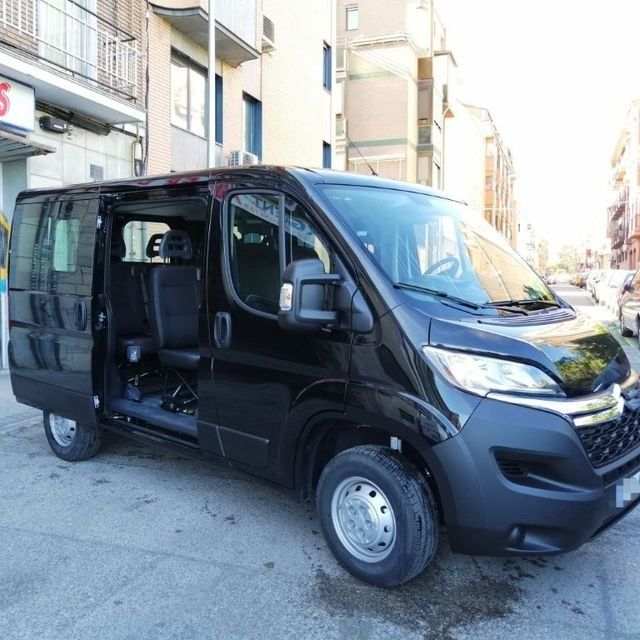 Una camioneta negra está estacionada frente a un edificio con la puerta abierta