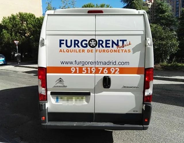 Una furgoneta blanca de Furgorent está estacionada al costado de la carretera.