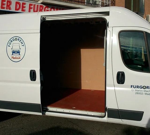 Una furgoneta blanca Furgonet está estacionada frente a un edificio.