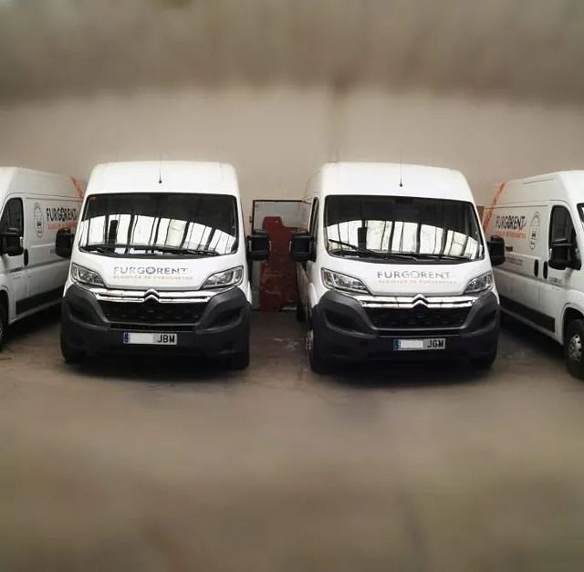 Una fila de furgonetas blancas están estacionadas en un almacén.