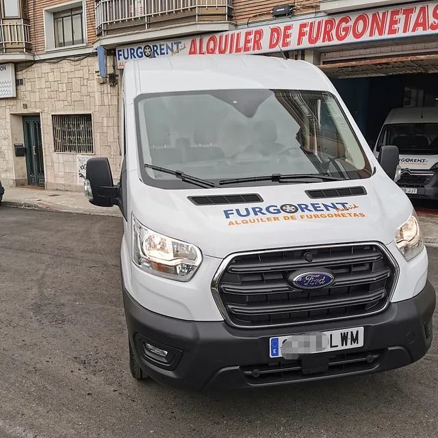 Una camioneta Ford blanca está estacionada frente a un edificio que dice furgonetas