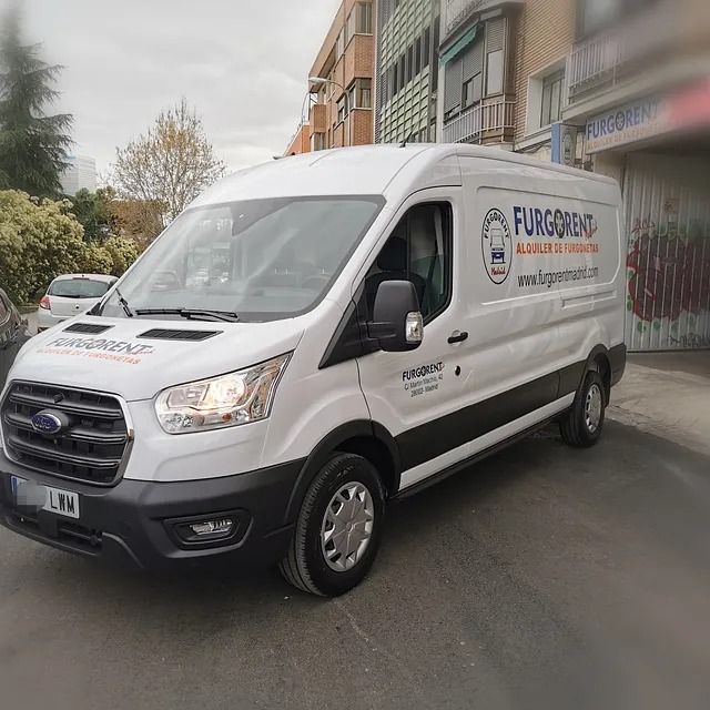 Una camioneta blanca está estacionada frente a un edificio.