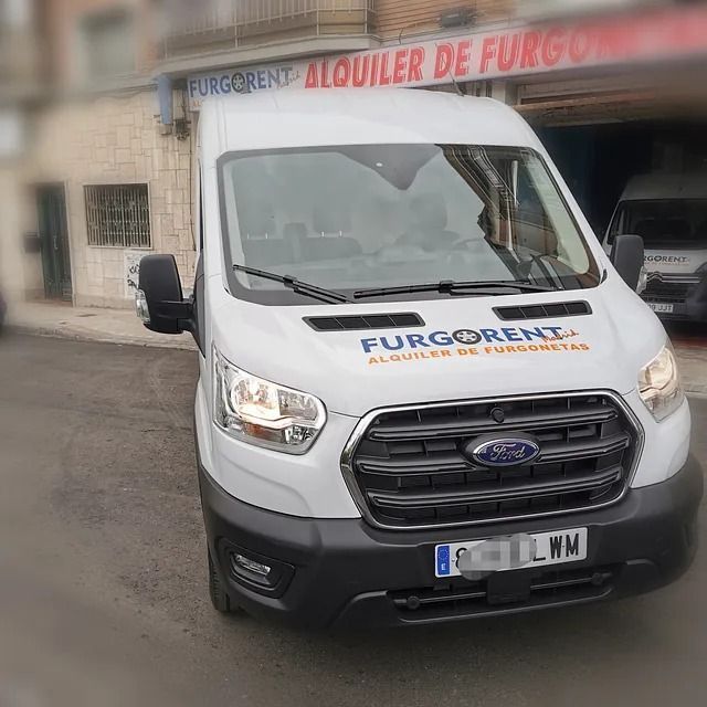 Una furgoneta blanca Furgonet está estacionada frente a un edificio.
