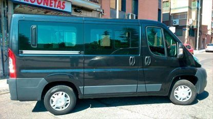 Una camioneta negra está estacionada al costado de la carretera frente a un edificio.