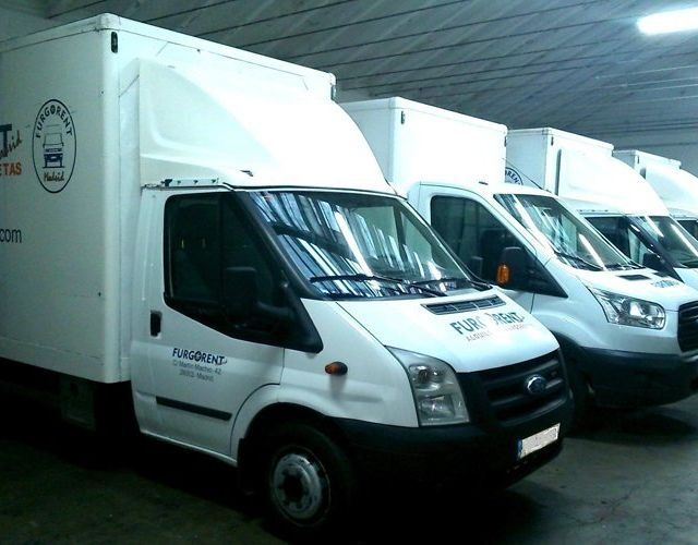 Una fila de furgonetas blancas están estacionadas en un almacén