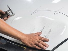 Ein Lackierer arbeitet an der Motorhaube eines Autos