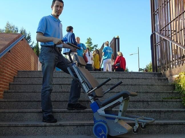 Un hombre empuja una silla por unas escaleras.