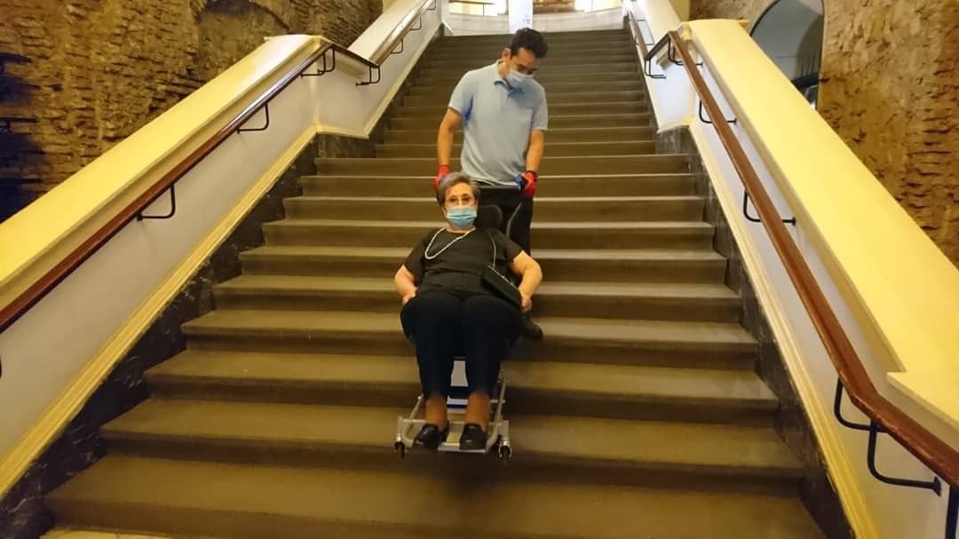 Hombre sosteniendo a mujer en silla de ruedas