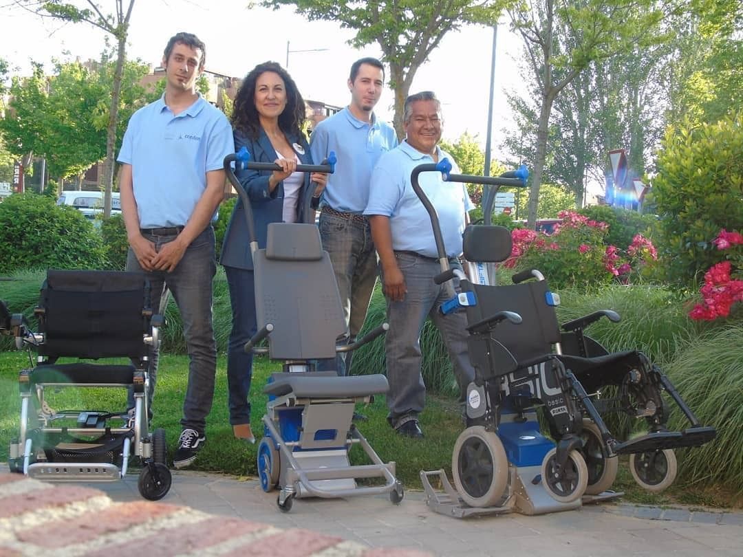 Un grupo de personas de pie junto a sillas de ruedas y scooters.