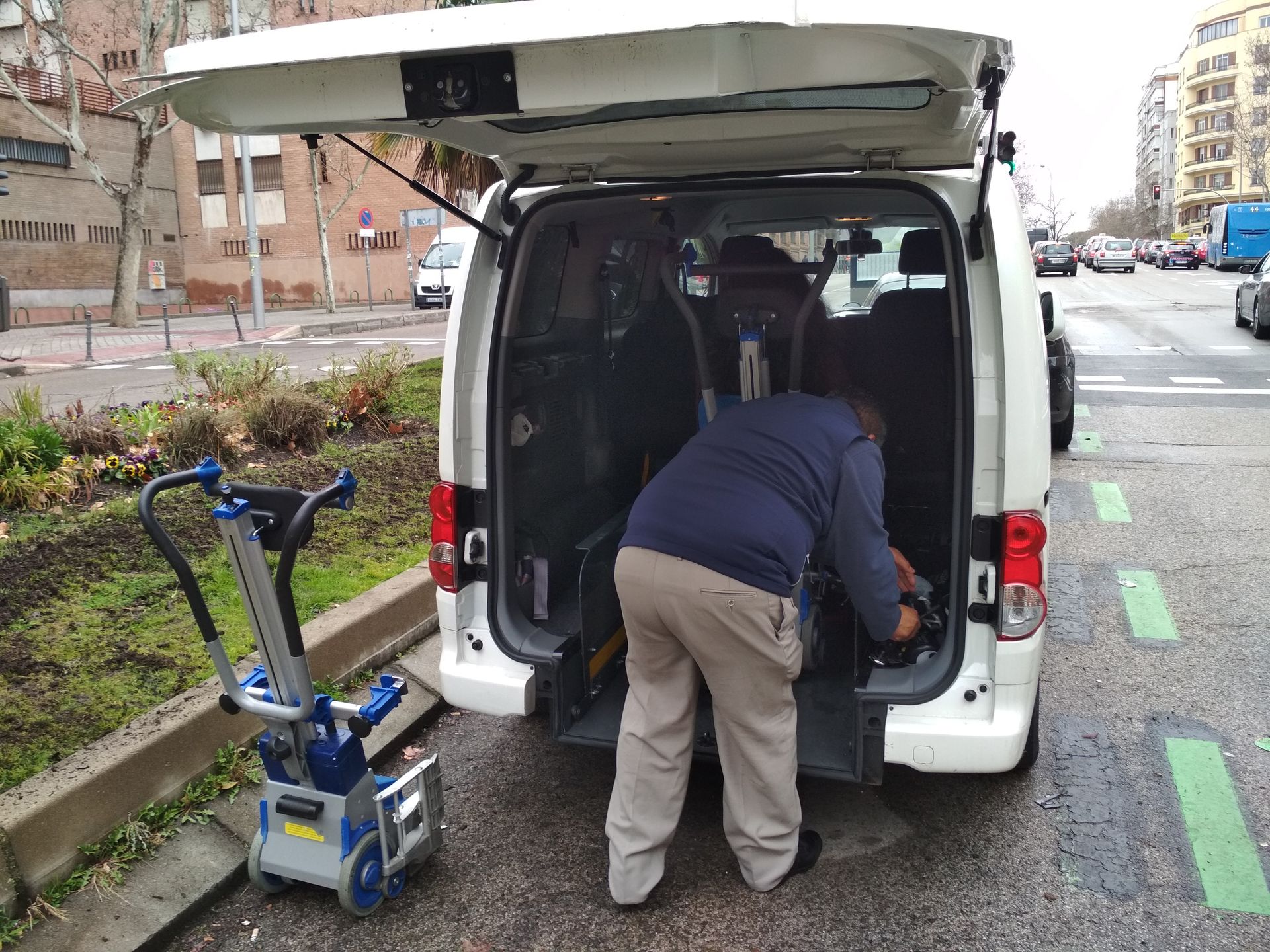Un hombre está cargando una silla de ruedas en la parte trasera de una camioneta.