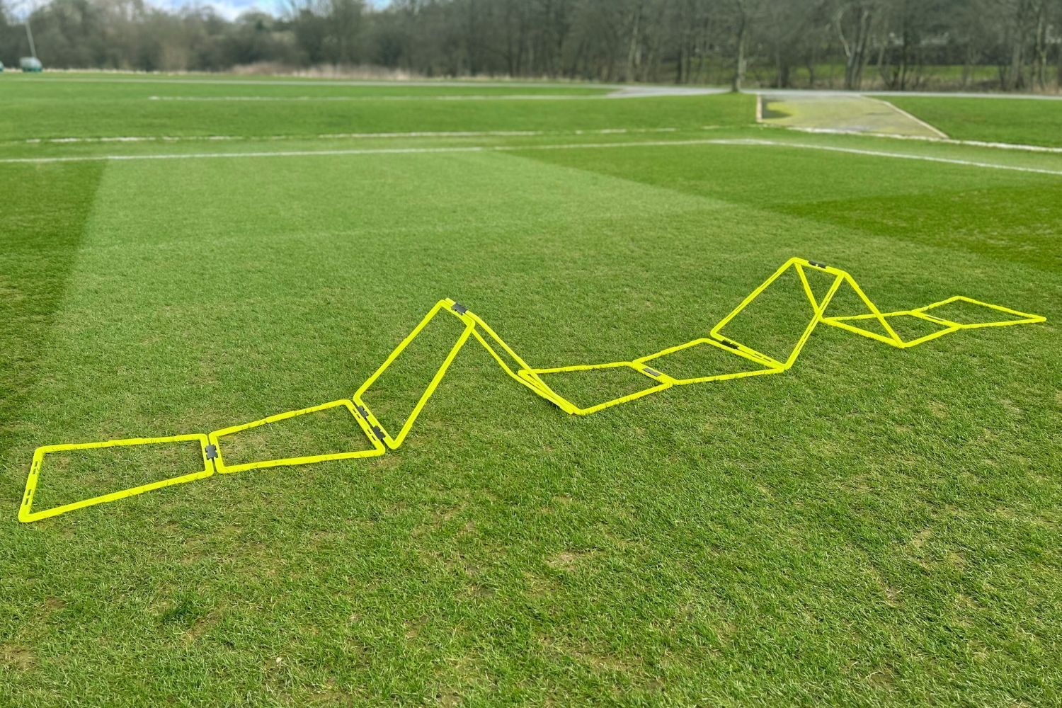 A person is holding a yellow ladder on a soccer field.