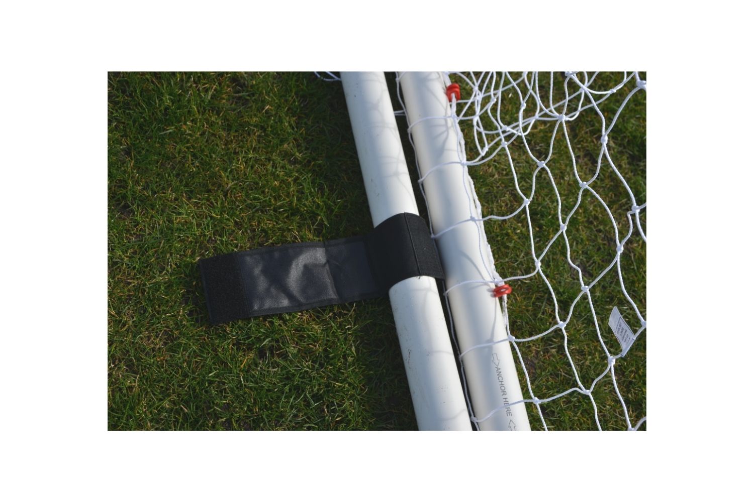 A soccer goal on a field with trees in the background