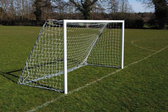 Soccer goal on a green field, with white posts and a net. The goal is empty, ready for play.