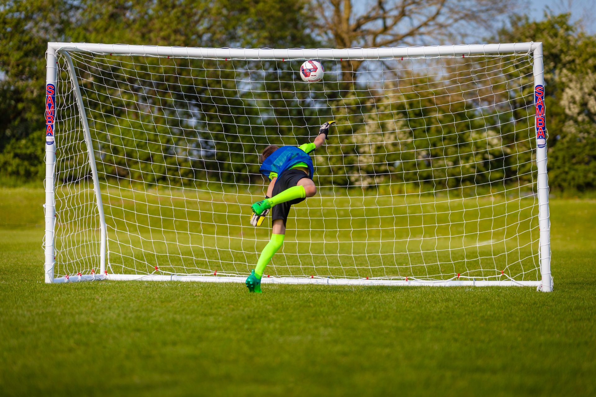 A soccer player kicking a ball into a goal with the word eagle on it