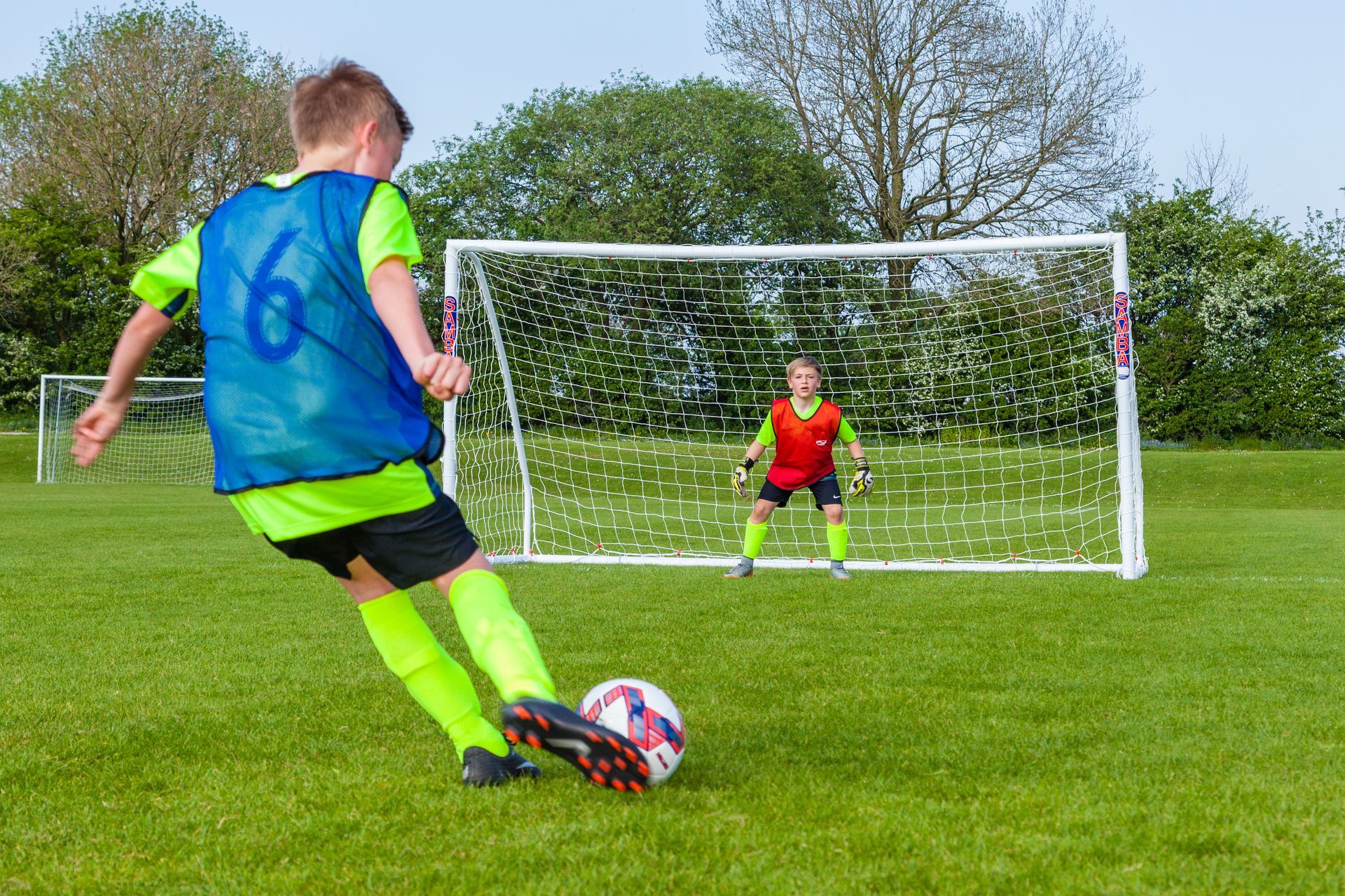 A soccer player kicking a ball into a goal with the word eagle on it