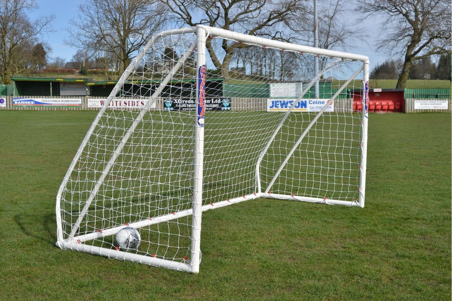 A soccer goal with a sign in the background that says tyres