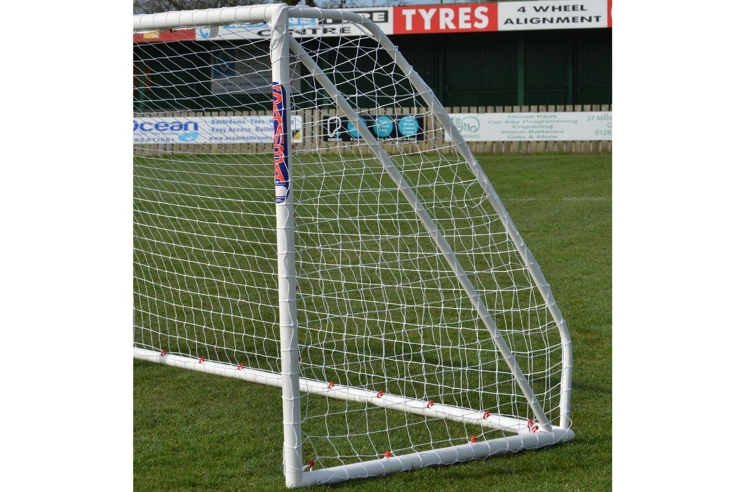 A soccer goal with a sign in the background that says tyres