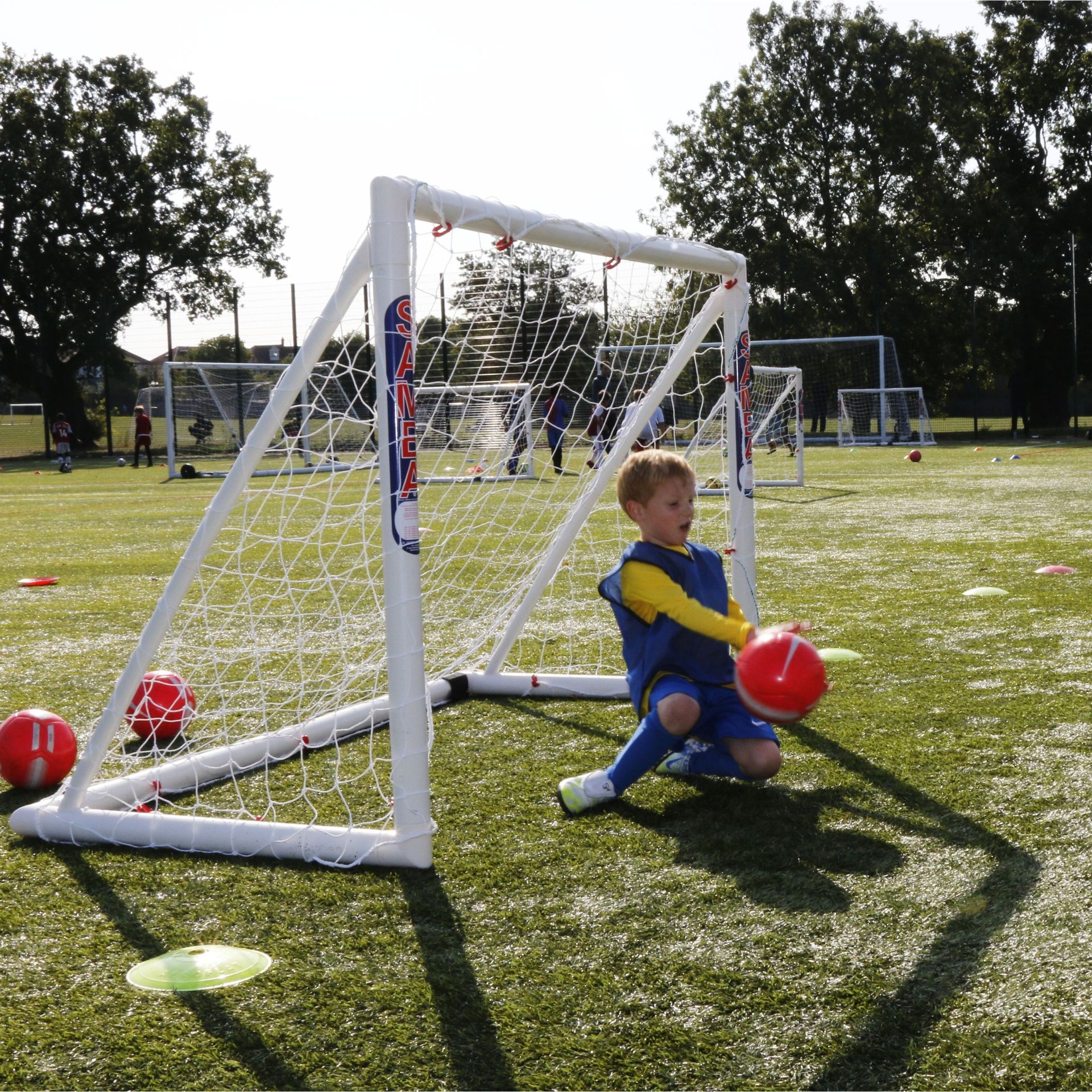 A young boy is kneeling in front of a soccer goal