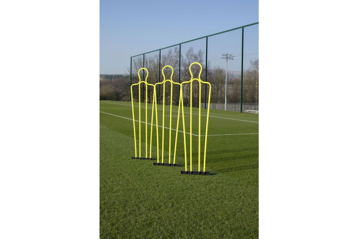 A row of yellow mannequins on a soccer field
