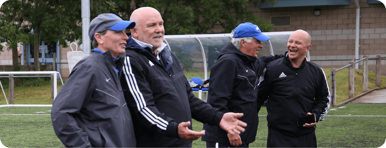 A group of men are standing on a soccer field talking to each other.