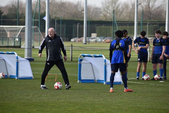 A young girl in a maroon shirt is kicking a soccer ball