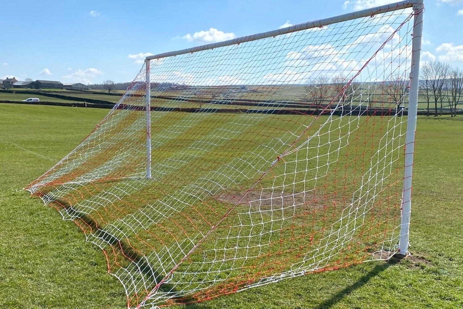 A soccer goal is sitting in the middle of a field