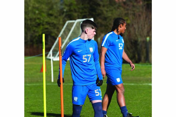 Two soccer players are walking on a field and one has the number 57 on his shirt