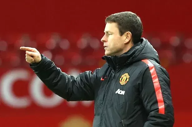 A man in a manchester united jacket is pointing at something