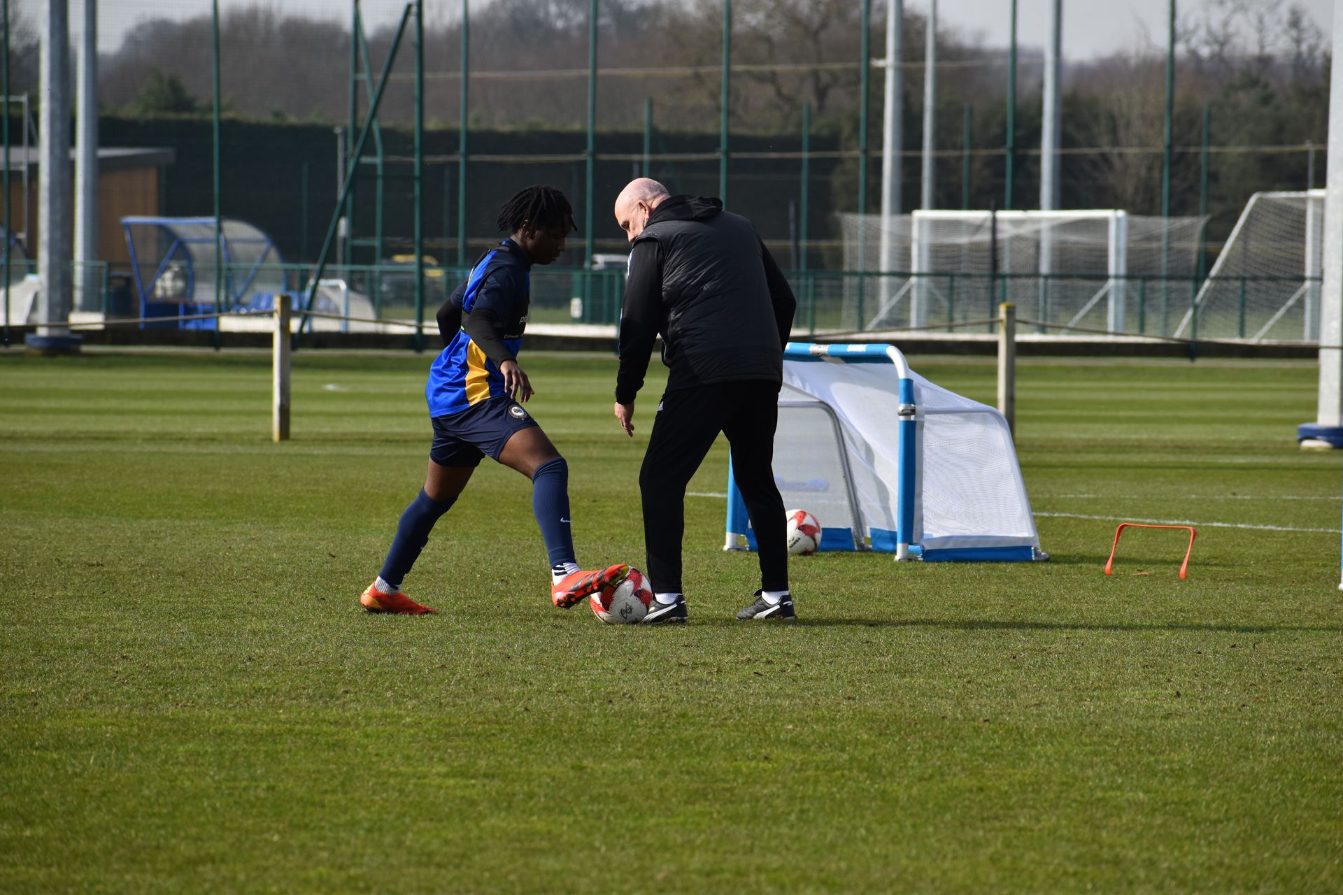 A man and a boy are playing soccer on a field