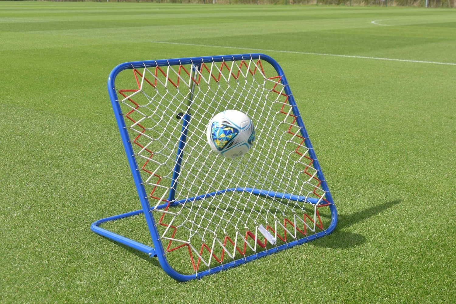 A soccer ball is going through a net on a field