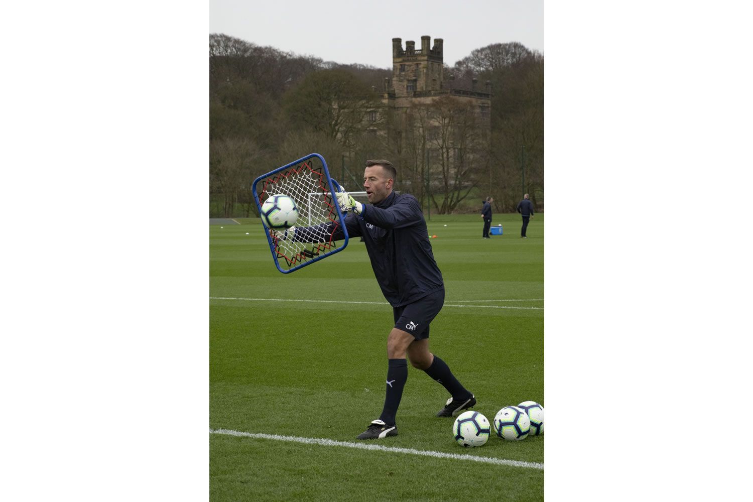 A soccer ball is sitting in front of a net on a field