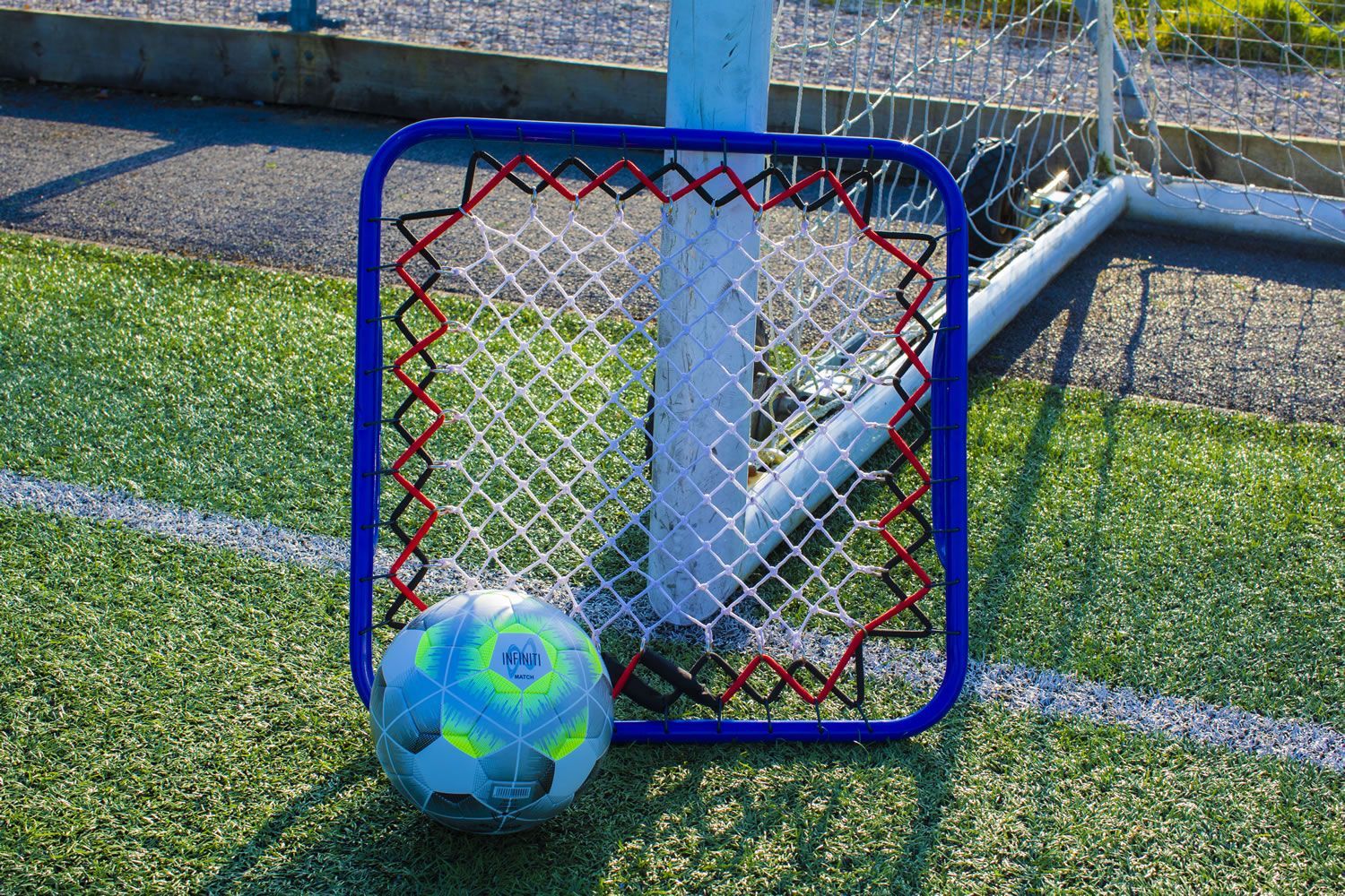 A soccer ball is sitting in front of a net on a field