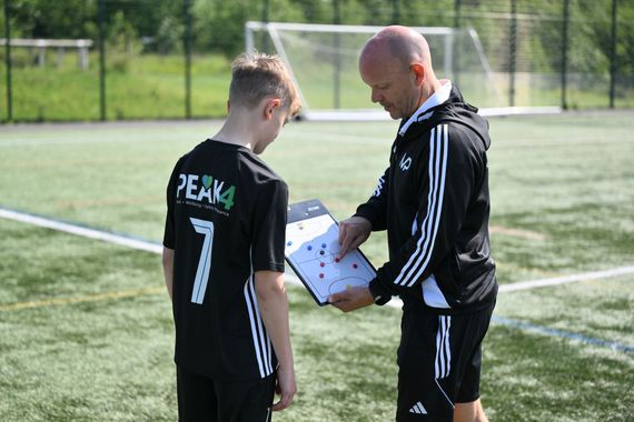 Soccer goal on a green field, with white posts and a net. The goal is empty, ready for play.