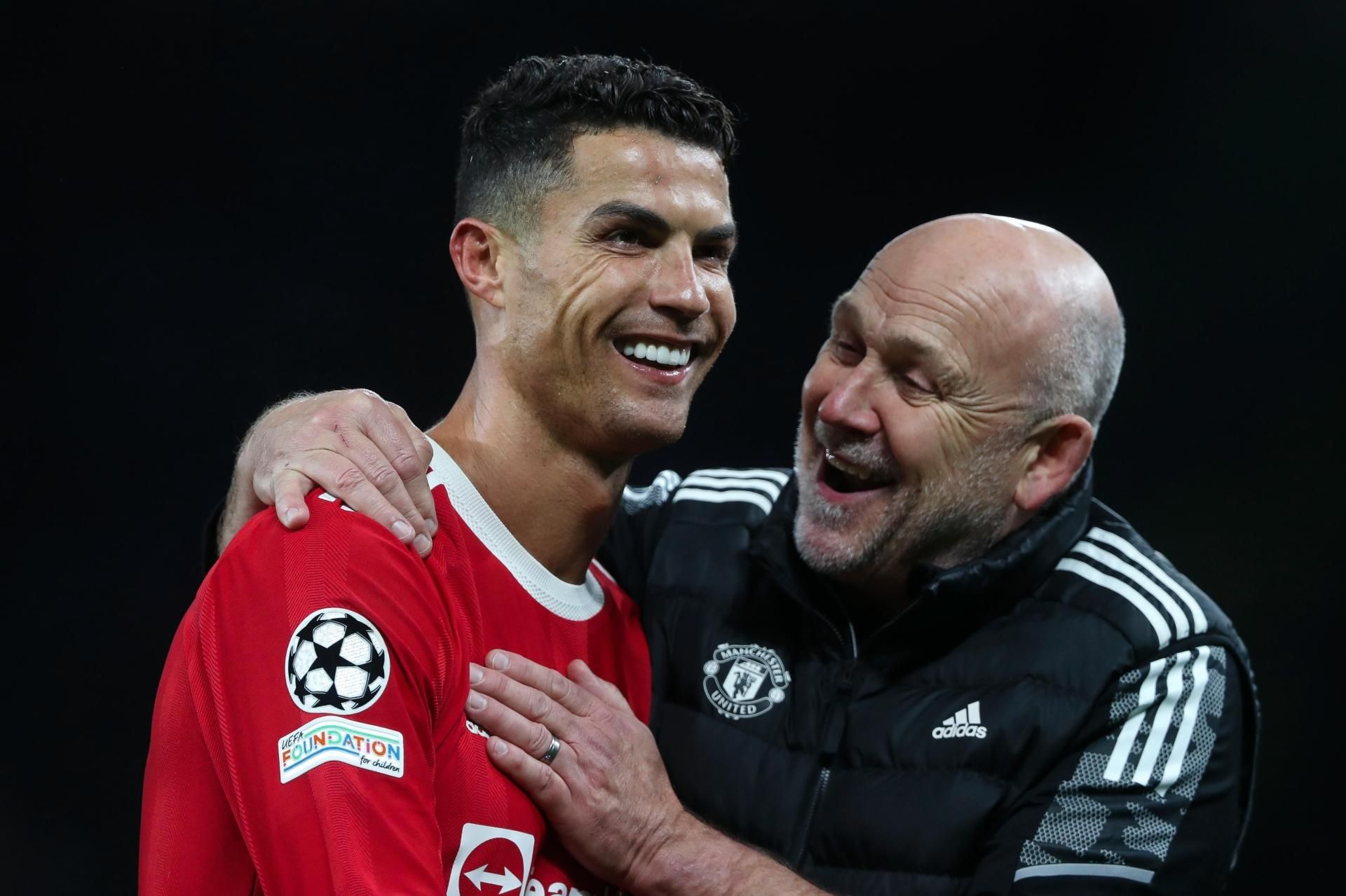 A man in a red shirt is hugging another man in a black jacket.