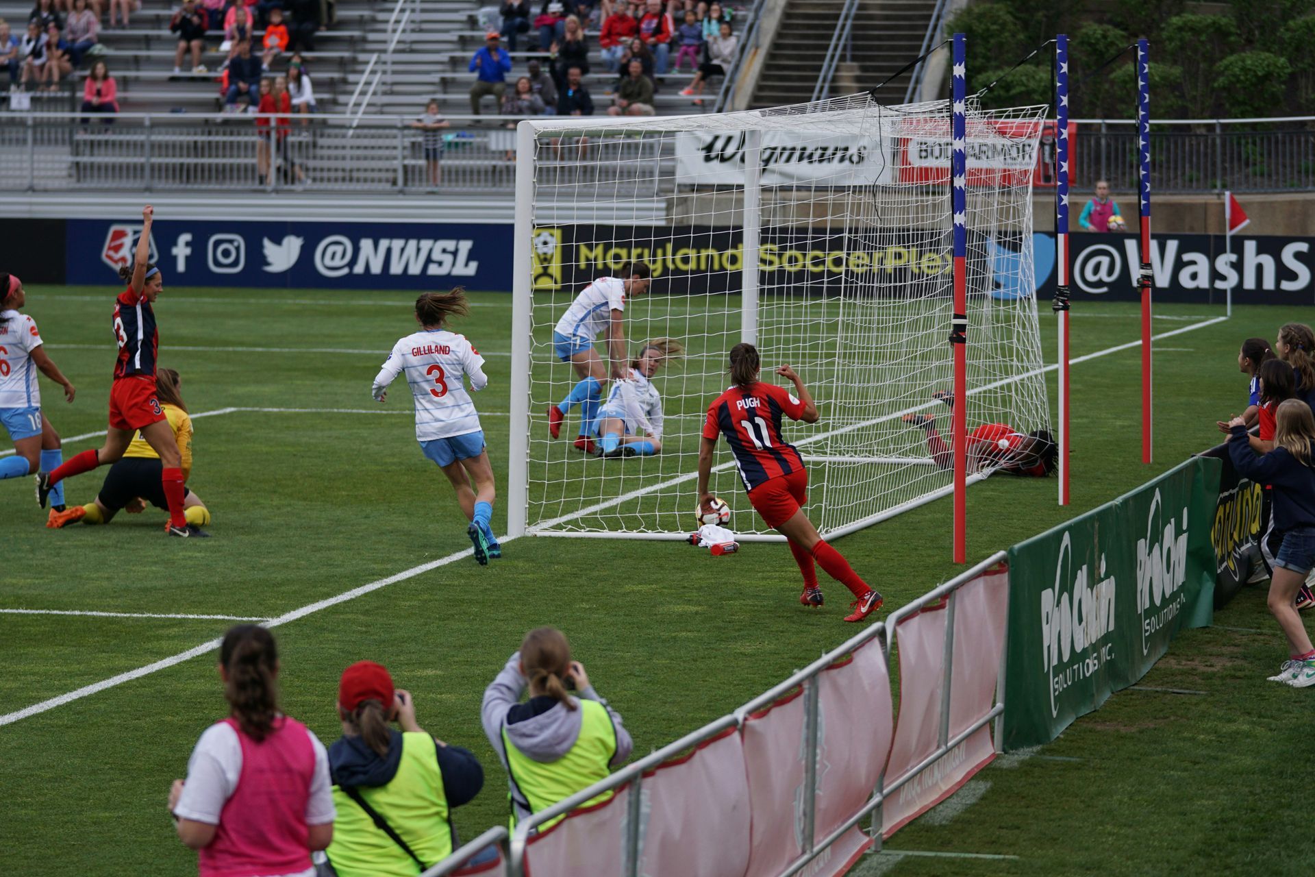 A soccer game is being played in front of a banner that says washs