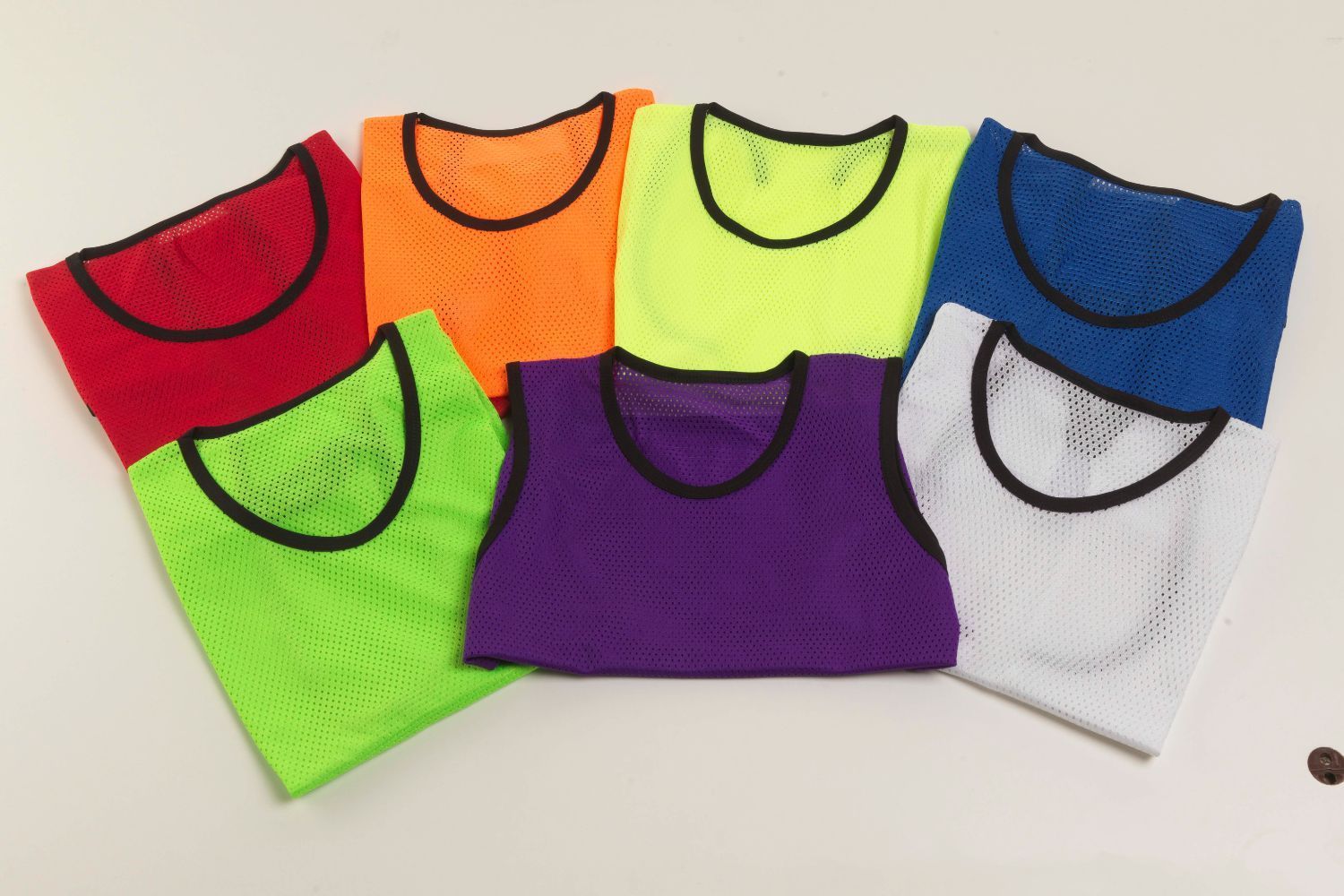 A bunch of different colored mesh vests are stacked on top of each other