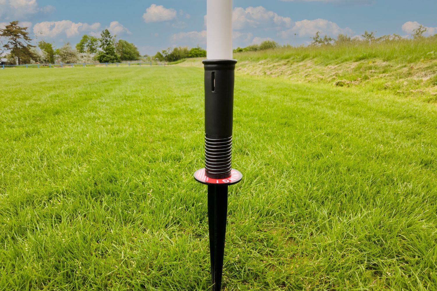 An orange flag on a white pole in a grassy field