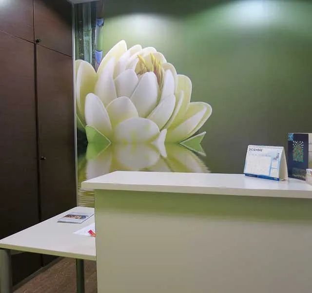 Un mostrador de recepción con una imagen de una flor en la pared detrás de él.