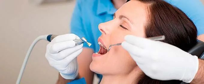 Una mujer está siendo examinada por un dentista.