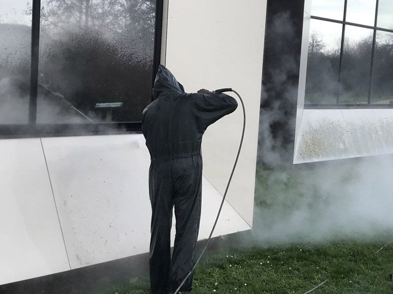 Une personne nettoyant la façade d'un bâtiment professionnel