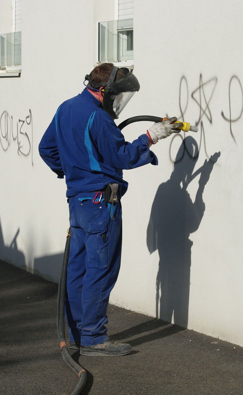 Nettoyeur utilisant un appareil à aérogommage sur un graffiti