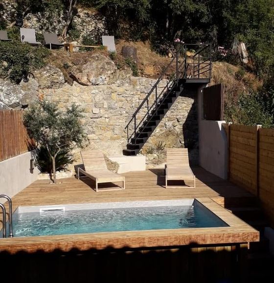 Terrasse à flanc de colline, avec une petite piscine, deux chaises longues et escalier en pierre.