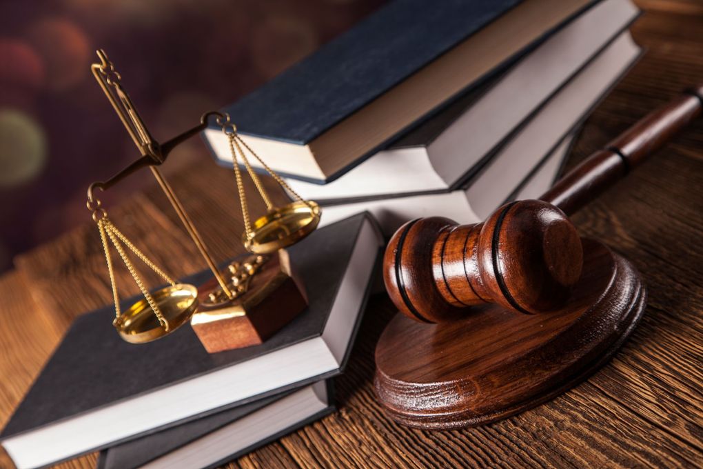 El mazo de un juez y la balanza de la justicia están sobre una mesa de madera.