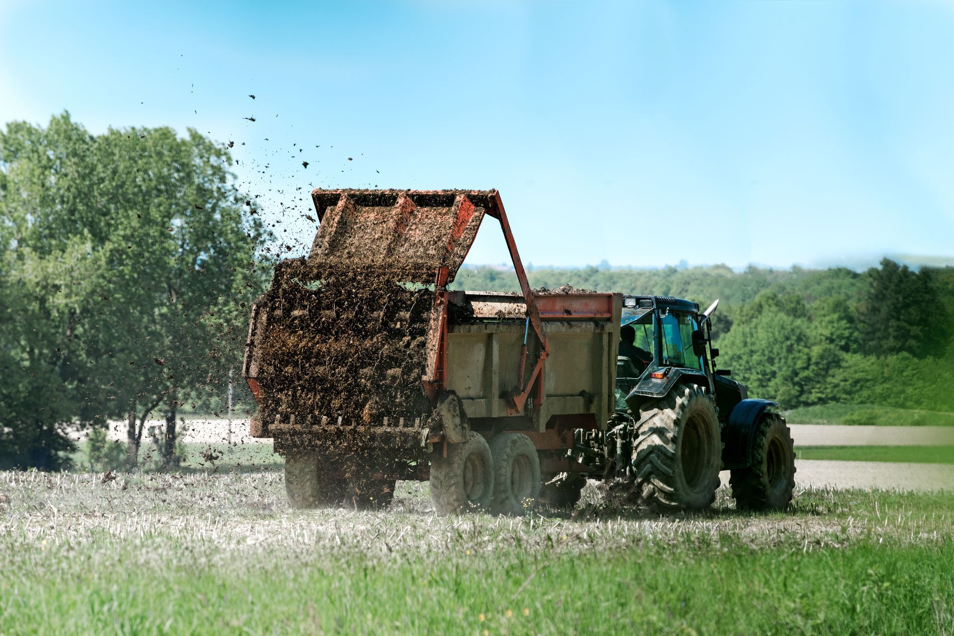 Une machine agricole en train d'épandre du fumier dans un champ.