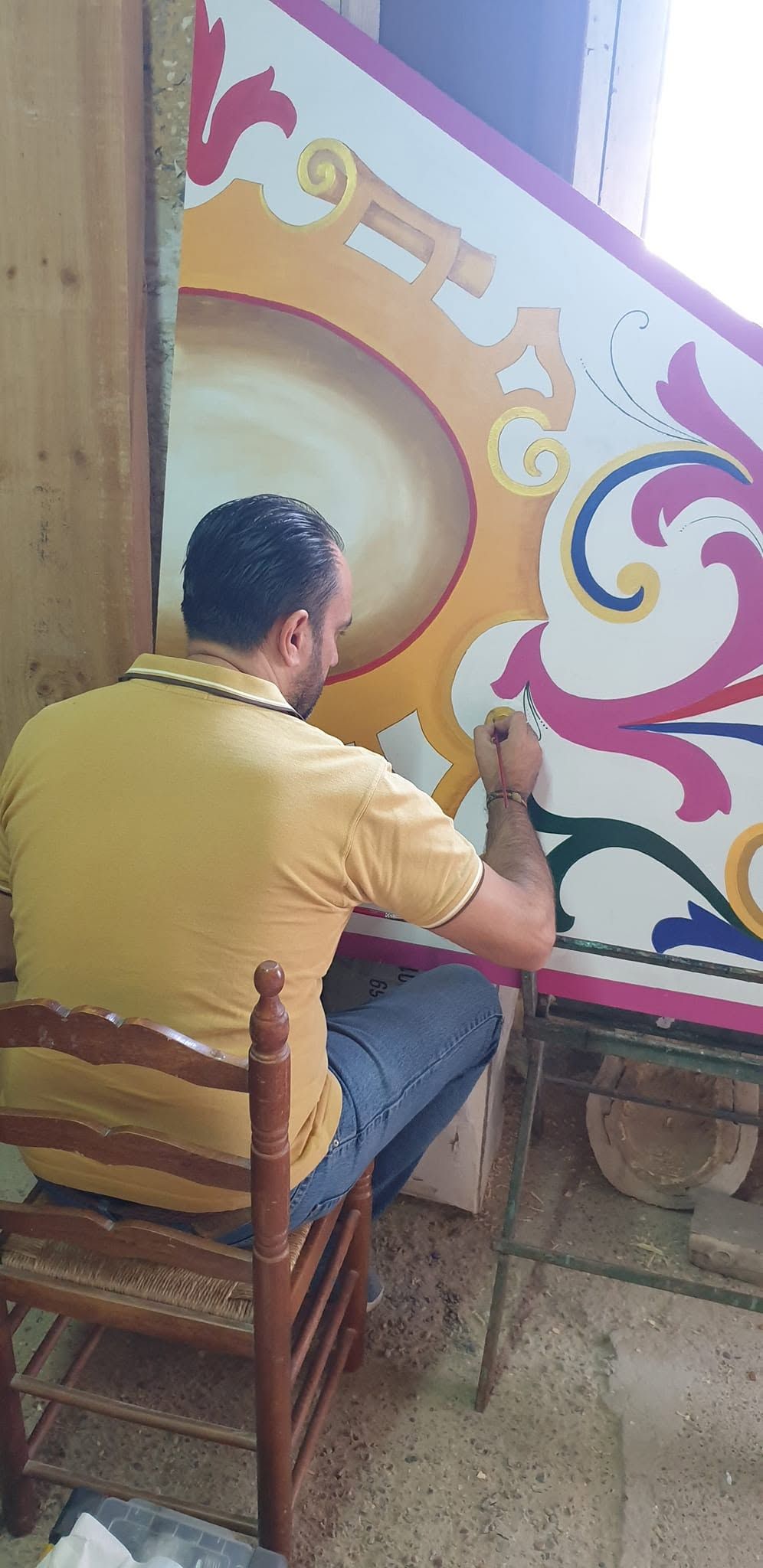 Persona pintando un mural decorativo con espirales de colores y un gran diseño circular.