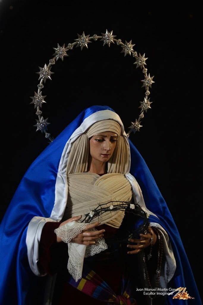 Estatua de una mujer velada con túnica azul que sostiene a un bebé, con un halo de estrellas detrás de ella.