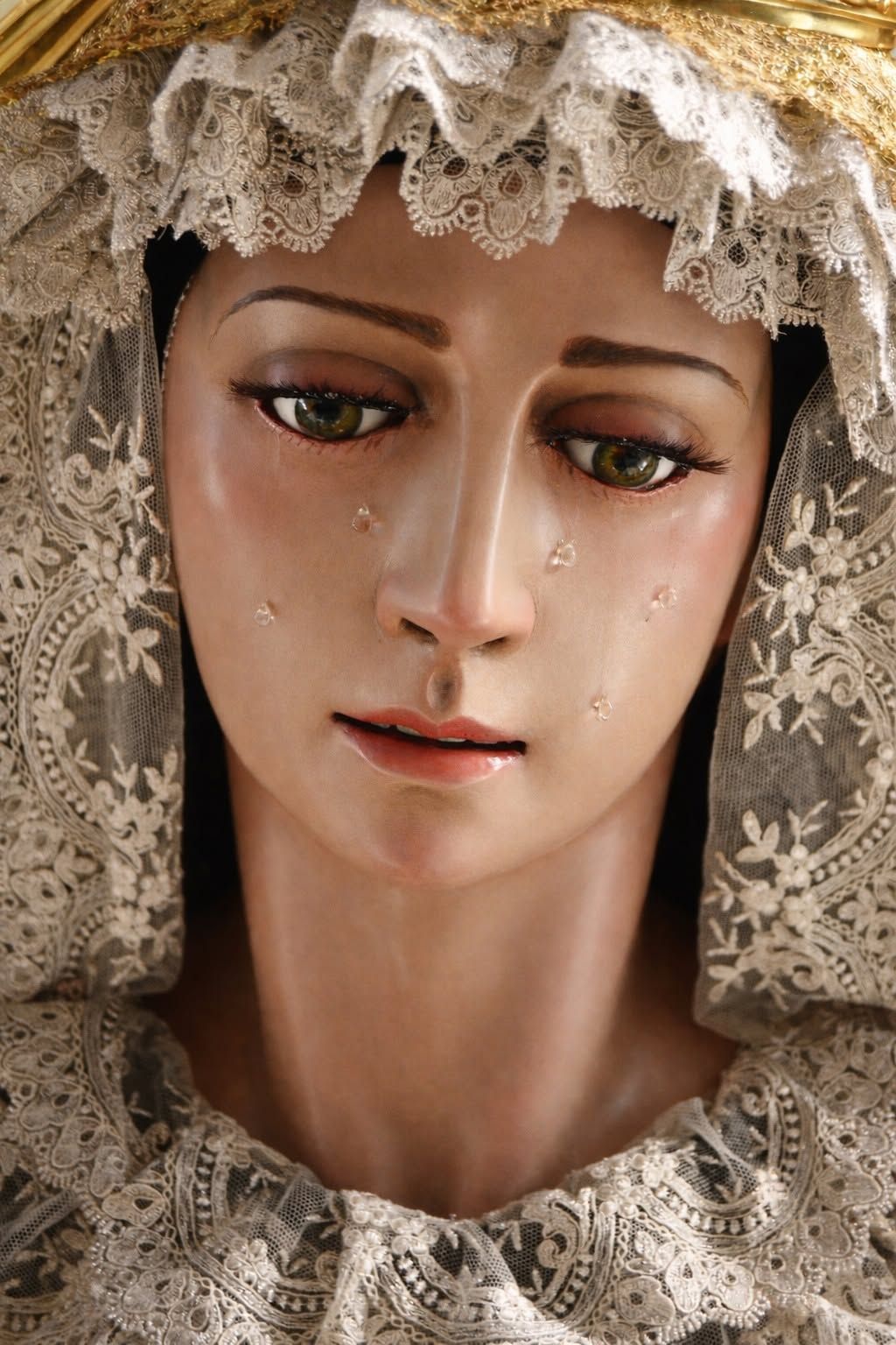 Primer plano del rostro triste de una muñeca de porcelana con velo de encaje y lágrimas.